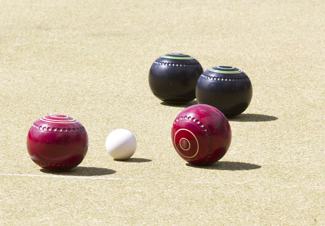 Red and Black Bocce Balls with Pallino on a Sand Court