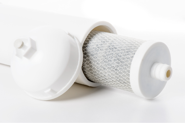 White portable water filter with extended carbon screen and cover positioned next to its body.